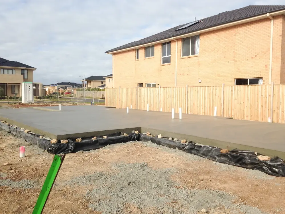 Concrete house slab being formed beside a residential building site with two-storey houses